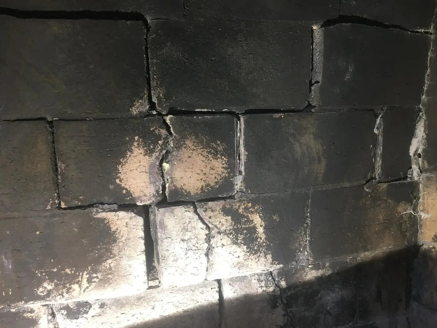 Cracked firebrick with soot stains inside a fireplace.